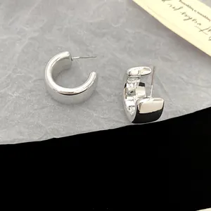 Close-up of minimalist silver chunky C-shaped hoop earrings with a glossy finish