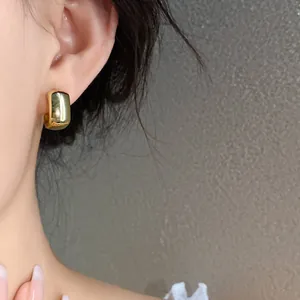 Close-up of a glossy gold C-shaped earring on a model's ear for a chic look