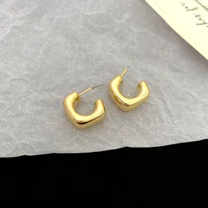 Detailed macro view of elegant gold geometric C-shaped stud earrings with a smooth finish