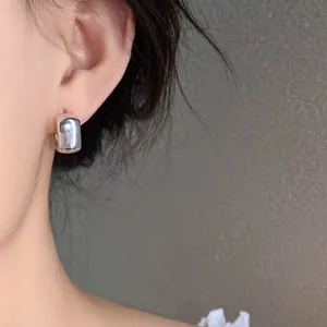 Detail shot of a minimalist silver geometric acrylic stud earring on a female ear