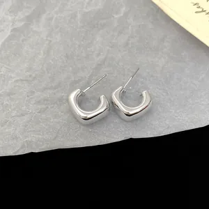 Close-up of minimalist silver geometric hoop earrings with a smooth polished finish