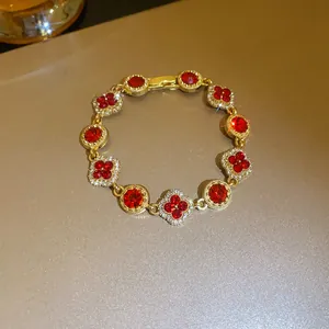 Close-up of sparkling red clover and round crystal bracelet in gold finish
