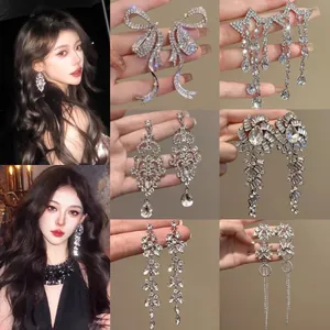 Detailed showcase of luxury silver rhinestone flower and water drop tassel earrings.