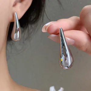Close-up of polished silver teardrop stud earrings worn on ear for a minimalist look.
