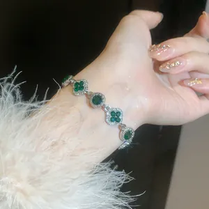Detail view of silver bracelet with green stones and four-leaf clover motifs on wrist