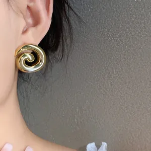 Close-up of a retro minimalist gold spiral acrylic stud earring worn on an ear
