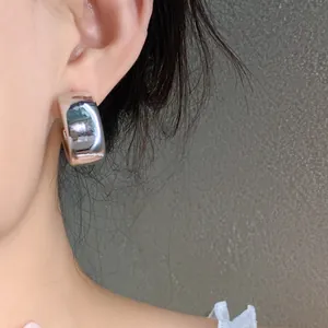 Detailed macro view of a chunky silver metallic geometric stud earring on model ear