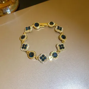 Detailed view of elegant gold bracelet with blue gemstones and sparkling flower motifs.
