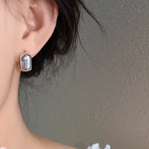 Close-up of silver geometric square stud earrings on ear for a minimalist jewelry style