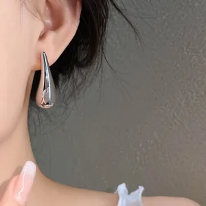 Detailed view of minimalist silver teardrop earring worn on model for retro style
