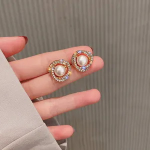 Vista detallada de elegantes pendientes dorados con perla blanca y brillantes strass