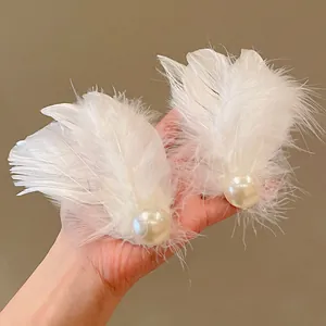 Detailed view of ethereal white feather hair clip featuring a large glossy central pearl
