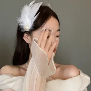 Close-up of model wearing white feather hair clip with pearl for bridal hair style