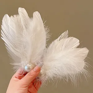 Detailed shot of an elegant white feather hair clip featuring large pearls on a warm background