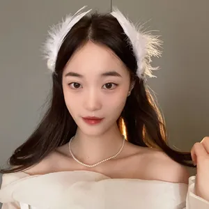 Elegant white fairy-style feather hair clip with pearl details worn by a beautiful model