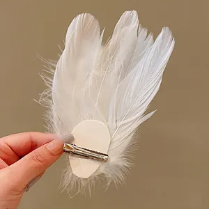 Detailed macro view of white feather hair clip showing the duckbill clip back.