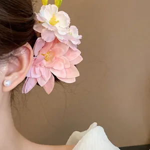 Nahaufnahme einer großen rosa Stoffblumen-Haarklammer, die an einem Haarknoten getragen wird