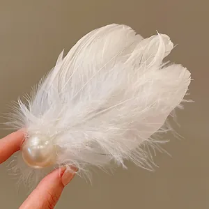 Close-up of ethereal white feather hair clip featuring a large lustrous pearl detail