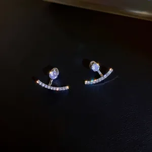 Primer plano de elegantes pendientes de plata en forma de media luna con piedras brillantes