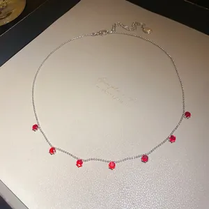 Gros plan sur un collier en argent orné de sept zircons ronds rouges étincelants