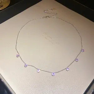 Vue détaillée d'un collier de couleur argentée avec sept pendentifs en zircone violette.