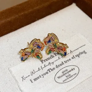 Detailed close-up of 18K gold plated colorful zircon horse stud earrings on fabric