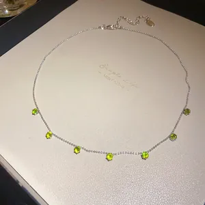 Détail d'un collier en argent orné de zircons ronds verts étincelants et élégants.