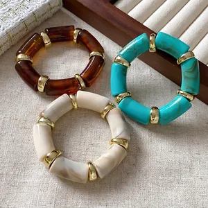 Stack of three bohemian marbled cylindrical elastic bracelets with gold spacers
