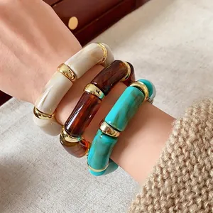 Bohemian ink-wash cylindrical stretch bracelet set with gold-tone metal spacers on wrist
