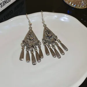 Detailed macro view of antique silver ethnic style earrings featuring carved flower tassels