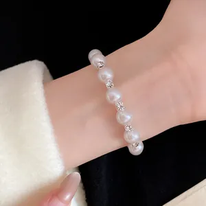 Close-up detail of a vintage pearl beaded open bangle with rhinestone accents on wrist