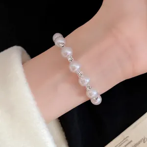 Elegant pearl beaded bracelet with rhinestone spacers shown in detail on a model's wrist