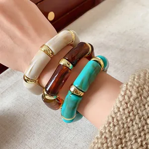 Detail of bohemian marbled cylinder elastic bracelets with gold spacers on wrist