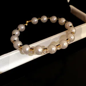 Close-up detail of an elegant pearl beaded bangle with sparkling gold diamond spacers
