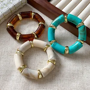 Close-up of bohemian cylindrical elastic bracelets with marble texture and gold beads