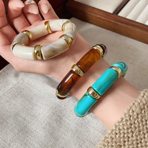 Detailed close-up of bohemian style marble-effect cylindrical elastic bracelets on a wrist.