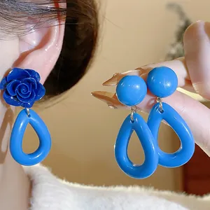 Détail rapproché de boucles d'oreilles géométriques en acrylique bleu sur modèle