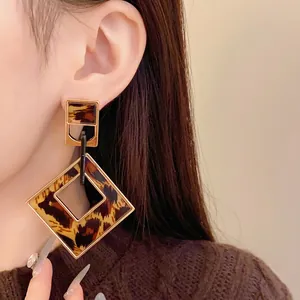 Vintage leopard print hollow diamond earrings with gold-tone borders on an Asian model