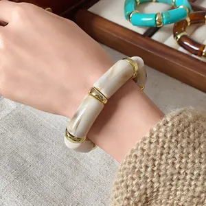 Detail view of a bohemian marbled cylindrical elastic bracelet with gold accents on a wrist