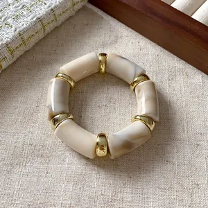 Close-up detail of a bohemian marbled cylindrical bead bracelet with gold-tone spacers.