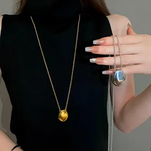 Detail of minimalist gold and silver pebble pendant necklaces on a black turtleneck