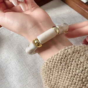 Elegant marbled cylinder elastic bracelet with gold spacers shown on a model's wrist