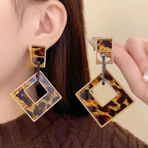 Close-up of stylish hollow geometric leopard print earrings with gold-tone hardware.