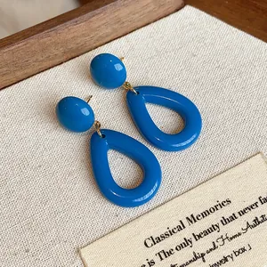 Gros plan de boucles d'oreilles pendantes en acrylique bleu rétro sur présentoir tissu