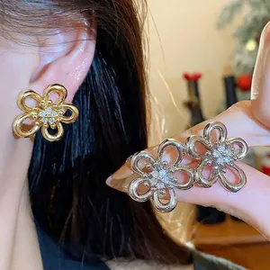 Elegant zircon floral stud earrings in gold and silver finish, shown on model's ear.