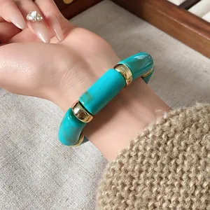 Close-up of bohemian turquoise marble cylindrical bead stretch bracelet with gold spacers