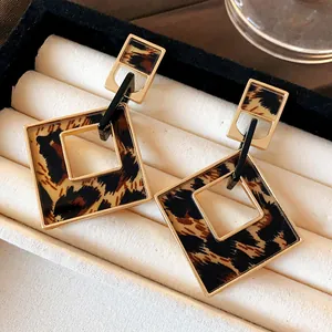 Macro detail of leopard print hollow geometric earrings displayed in a luxury jewelry box