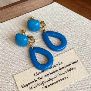 Vue détaillée de boucles d'oreilles en acrylique bleu sur un support en bois chic