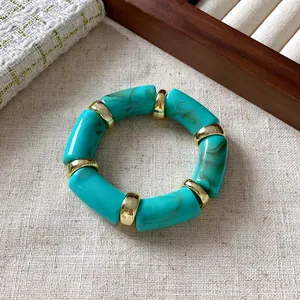 Close-up of bohemian marble turquoise bead bracelet with gold spacers on textured fabric