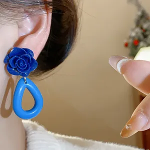 Gros plan de boucles d'oreilles rose acrylique bleue et goutte géométrique portées